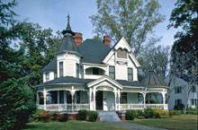 белые дощатые фасады дома с темно-серой битумной черепицей